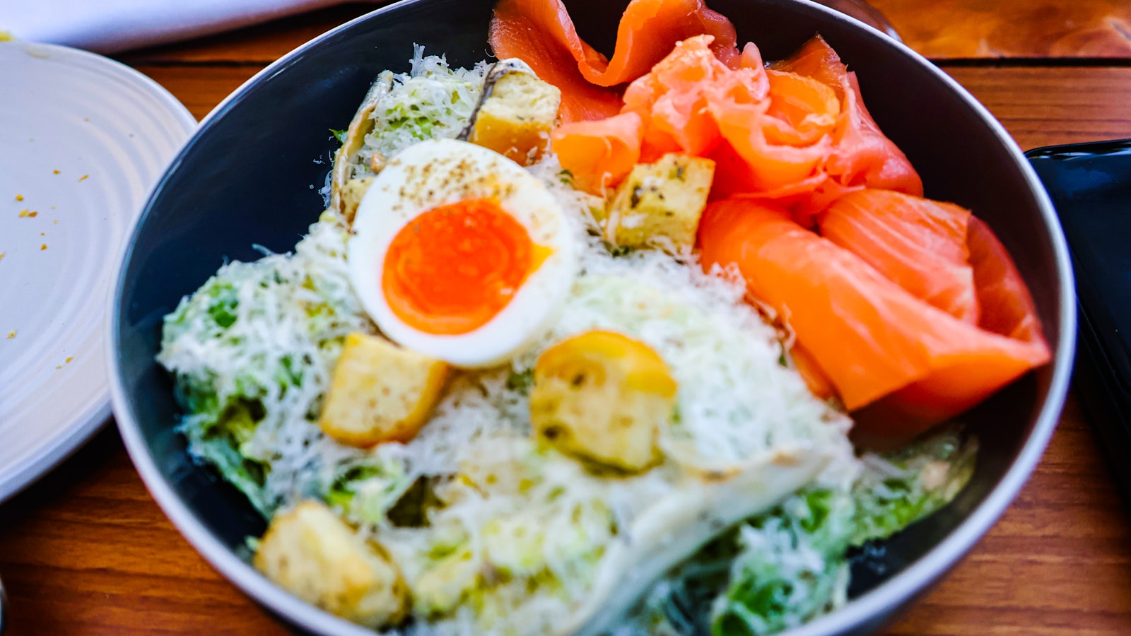 Kom met zalm, een gekookt ei en groene salade