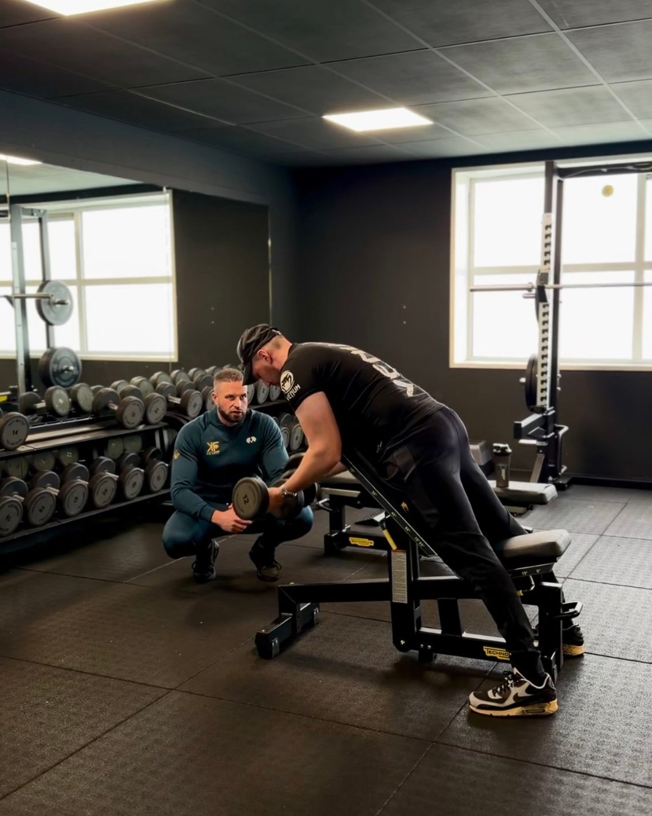 Kevin Aalbers begeleidt een klant tijdens een oefening met dumbbells