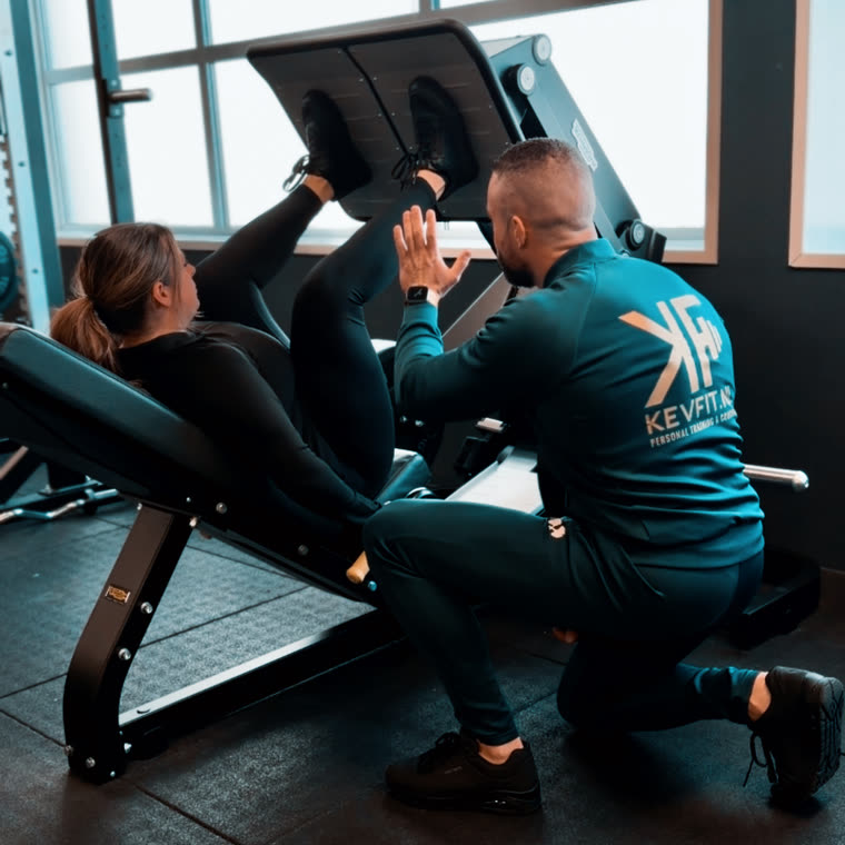 Kevin begeleidt een klant op de legpress
