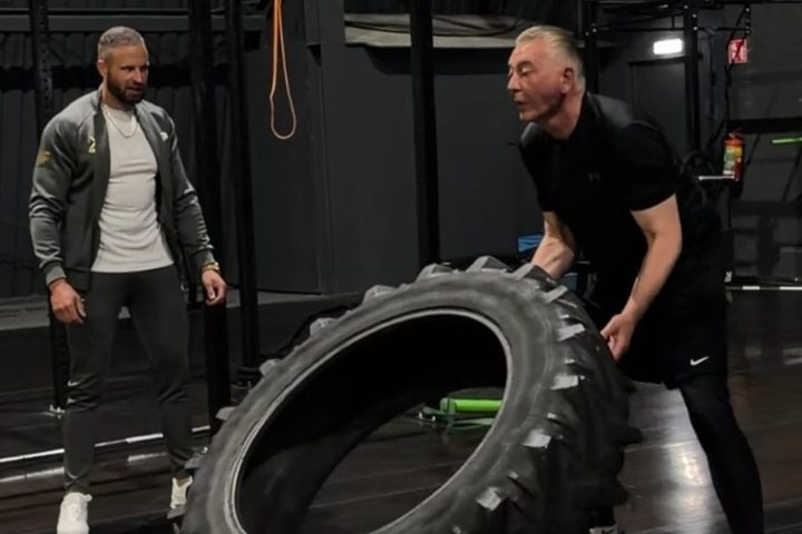Een klant traint met een trekkerband terwijl Kevin Aalbers meekijkt
